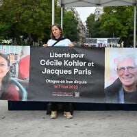 People hold a banner reading "Freedom for Cecile Kohler and Jacques Paris hostages in Iran since May 7, 2022," as they gather to celebrate the 41st birthday of Kohler, held in Iran since May 2022 on spying charges, in Paris, France, on September 25, 2025. (Bertrand GUAY / AFP)