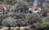 Israeli soldiers and an armored vehicle deploy as Palestinians and first responders try to extinguish a burning car set ablaze during an Israeli settler attack in Beita, south of Nablus, on October 10, 2025, amid the annual olive harvest. (Jaafar Ashtiyeh / AFP)