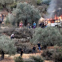 Israeli soldiers and an armored vehicle deploy as Palestinians and first responders try to extinguish a burning car set ablaze during an Israeli settler attack in Beita, south of Nablus, on October 10, 2025, amid the annual olive harvest. (Jaafar Ashtiyeh / AFP)