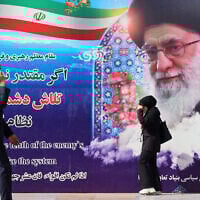 Iranians walk past a poster featuring Iran's Supreme Leader Ayatollah Ali Khamenei outside the venue of the 22nd Police and Security Equipment Exhibition at Imam Khomeini Mosque in Tehran, Iran, on October 15, 2025. (ATTA KENARE / AFP)