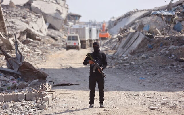 Illustrative: An armed Palestinian gunman stands not far from an International Red Cross (ICRC) vehicle, as a search for the bodies of slain Israeli hostages takes place, in Gaza City on November 2, 2025. (Omar AL-QATTAA / AFP) Illustrative: An armed Palestinian gunman stands not far from an International Red Cross (ICRC) vehicle, as a search for the bodies of slain Israeli hostages takes place, in Gaza City on November 2, 2025. (Omar AL-QATTAA / AFP)