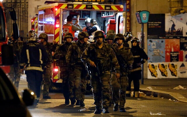 French soldiers walk in front of an ambulance as rescue workers evacuate victims near La Belle Equipe, rue de Charonne, at the site of an attack, in Paris on November 14, 2015, following a series of Islamist terror attacks across the French capital. (PIERRE CONSTANT / AFP)