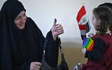 An Iraqi voter shows her ink-marked thumb to her family members after casting her ballot at a polling station in the southern city of Basra on November 11, 2025 during Iraq's parliamentary elections. (Hussein FALEH / AFP)