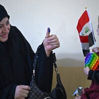 An Iraqi voter shows her ink-marked thumb to her family members after casting her ballot at a polling station in the southern city of Basra on November 11, 2025 during Iraq's parliamentary elections. (Hussein FALEH / AFP)