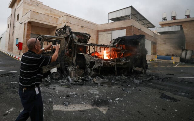 A Palestinian man uses a mobile phone to record a burning truck after an Israeli settlers attack in the village of Beit Lid, east of Tulkarm in the occupied West Bank on November 11, 2025. (Photo by JAAFAR ASHTIYEH / AFP)