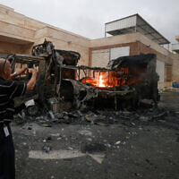 A Palestinian man uses a mobile phone to record a burning truck after an Israeli settler attack in the village of Beit Lid, east of Tulkarm, West Bank, on November 11, 2025. (JAAFAR ASHTIYEH / AFP)