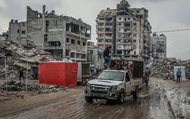 Palestinians drive down a muddy road after the first winter rainfall in a displacement camp in Gaza City on November 14, 2025. (Omar al-Qattaa/AFP)