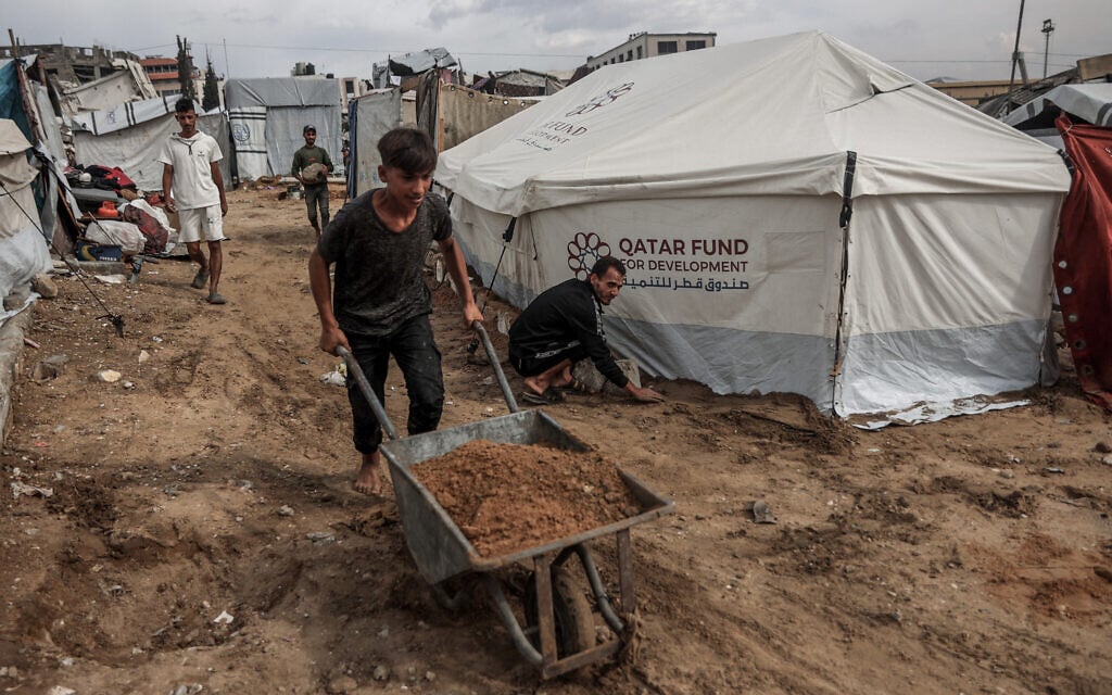 Palestinian men fix their makeshift shelters as the first winter rains fall on a displacement camp in Gaza City on November 14, 2025.  (Photo by Omar AL-QATTAA / AFP)