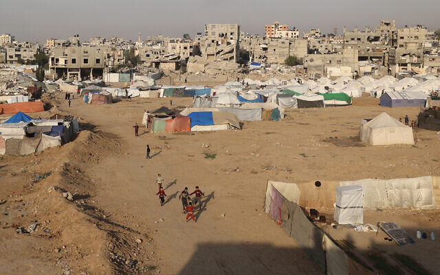 Children play near shelters and tents in the Bureij camp in the central Gaza Strip, on November 18, 2025. (Eyad Baba / AFP)