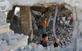 Illustrative: Palestinian boys walk amid the debris of a building in Gaza City's Zeitoun neighborhood following an Israeli airstrike, November 20, 2025. (Omar AL-QATTAA / AFP)