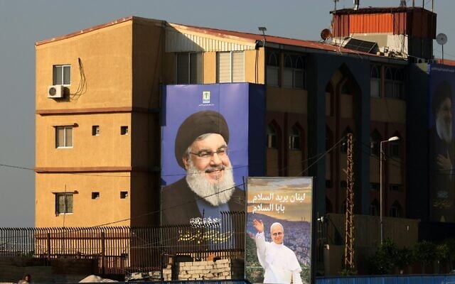 A poster of Pope Leo XIV hangs near a billboard of assassinated Hezbollah leader Hassan Nasrallah on the highway that leads to Beirut's international airport on November 20, 2025. (Photo by Anwar AMRO / AFP) A poster of Pope Leo XIV hangs near a billboard of assassinated Hezbollah leader Hassan Nasrallah on the highway that leads to Beirut's international airport on November 20, 2025. (Photo by Anwar AMRO / AFP)