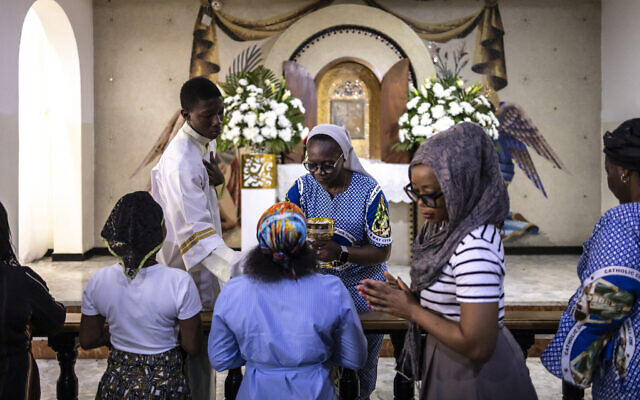 (FILES) A nun imparts the holy communion to Catholics attending a mass at the Church of the Assumption in Lagos on April 21, 2025. (Photo by OLYMPIA DE MAISMONT / AFP)