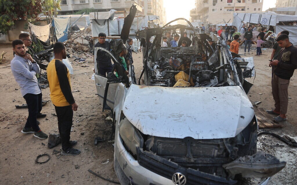 Palestinians gather to look at a destroyed vehicle targeted by the military, in Gaza City, on November 22, 2025. (Omar AL-QATTAA / AFP)