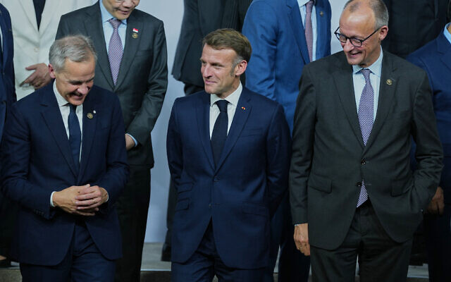 Canada's Prime Minister Mark Carney (L), France's President Emmanuel Macron and German Chancellor Friedrich Merz stand together as they attend a family photo event during a G20 Leaders' Summit plenary session at the Nasrec Expo Centre in Johannesburg on November 22, 2025. (Photo by Misper Apawu / POOL / AFP) Canada's Prime Minister Mark Carney (L), France's President Emmanuel Macron and German Chancellor Friedrich Merz stand together as they attend a family photo event during a G20 Leaders' Summit plenary session at the Nasrec Expo Centre in Johannesburg on November 22, 2025. (Photo by Misper Apawu / POOL / AFP)
