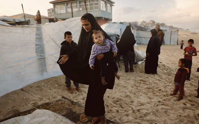 A Palestinian woman carries her child as she takes shelter from the rain at a makeshift camp housing displaced Palestinians in Deir al-Balah, in the central Gaza Strip on November 25, 2025 (Bashar Taleb / AFP) A Palestinian woman carries her child as she takes shelter from the rain at a makeshift camp housing displaced Palestinians in Deir al-Balah, in the central Gaza Strip on November 25, 2025 (Bashar Taleb / AFP)