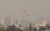 The Iranian flag flutters over the capital Tehran amid heavy winter smog pollution, November 25 2025. (ATTA KENARE / AFP)