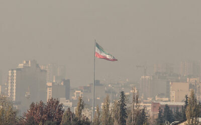 The Iranian flag flutters over the capital Tehran amid heavy winter smog pollution, November 25 2025. (ATTA KENARE / AFP)