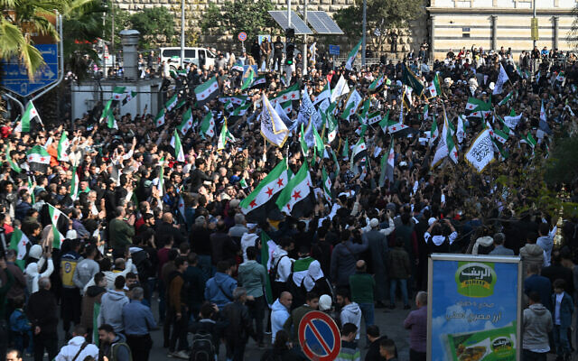 People hold flags as they celebrate the one year anniversary of the offensive that overthrew Syria's former president Bashar al-Assad, in central Damascus, on November 28, 2025. (LOUAI BESHARA / AFP) People hold flags as they celebrate the one year anniversary of the offensive that overthrew Syria's former president Bashar al-Assad, in central Damascus, on November 28, 2025. (LOUAI BESHARA / AFP)
