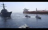 A frame grab from a video released by Iran's Revolutionary Guard on November 3, 2021, shows the Guard speed boats, center, in front of a US warship, left, amid the seizure of a Vietnamese-flagged oil tanker, right, in the Gulf of Oman. (Revolutionary Guard via AP)