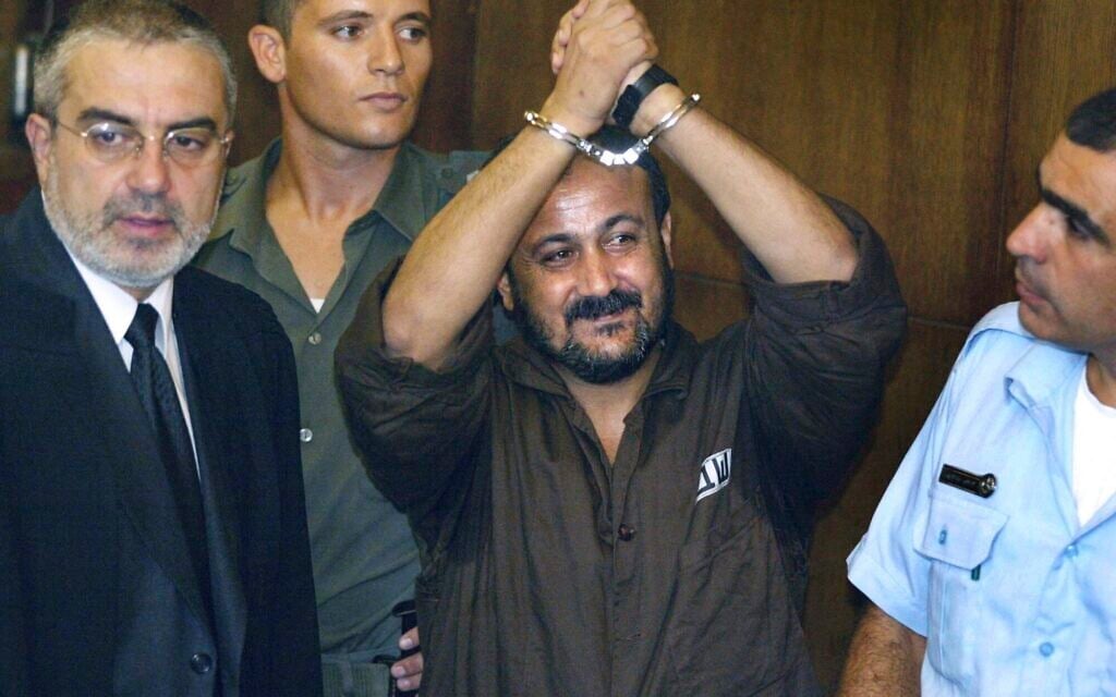 Marwan Barghouti, center, raises his handcuffed hands in the air on the opening day of his trial in Tel Aviv, Aug. 14, 2002. (AP/Brennan Linsley, File)