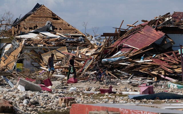 Residents make their way past piles of debris in the aftermath of Hurricane Melissa in Black River, Jamaica, October 30, 2025. (AP/Matias Delacroix)