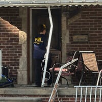 An FBI agent enters a home in a neighborhood of Dearborn, Michigan, on October 31, 2025. (Mike Householder/AP)
