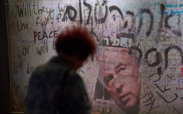 A woman sits by a wall covered with graffiti memorializing Yitzhak Rabin during a rally in Tel Aviv, Israel, on Saturday, November 1, 2025, marking 30 years since his assassination. (AP/Ariel Schalit)
