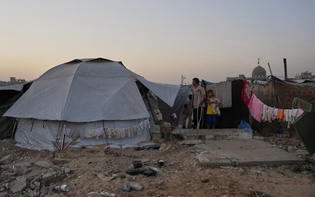 Mohammed Barabakh stands with his children at the entrance to his tent, which was set up next to graves in a cemetery in Khan Younis, in the southern Gaza Strip, October 31, 2025. (AP/Abdel Kareem Hana) Mohammed Barabakh stands with his children at the entrance to his tent, which was set up next to graves in a cemetery in Khan Younis, in the southern Gaza Strip, October 31, 2025. (AP/Abdel Kareem Hana)