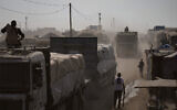 Armed men guard trucks carrying aid as they drive through Khan Younis, southern Gaza Strip, November 2, 2025. (AP Photo/Jehad Alshrafi)