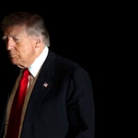 US President Donald Trump is illuminated by a camera flash as he walks across the South Lawn of the White House, in Washington, DC, November 2, 2025. (AP Photo/Mark Schiefelbein)