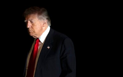 US President Donald Trump is illuminated by a camera flash as he walks across the South Lawn of the White House, in Washington, DC, November 2, 2025. (AP Photo/Mark Schiefelbein)