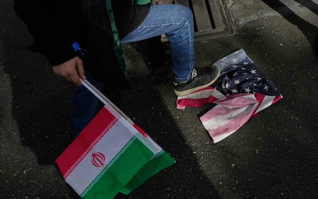 A school boy stomps a US flag as he holds an Iranian flag during an annual rally in front of the former US Embassy in Tehran, celebrating the anniversary of the 1979 takeover of the embassy, Nov. 4, 2025. (AP/Vahid Salemi)