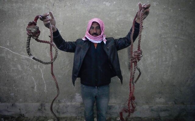 A man shows two ropes tied in the shape of nooses, found in the infamous Saydnaya military prison, just north of Damascus, Syria, December 9, 2024. (Hussein Malla/AP) A man shows two ropes tied in the shape of nooses, found in the infamous Saydnaya military prison, just north of Damascus, Syria, December 9, 2024. (Hussein Malla/AP)