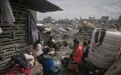 A family sits outside their damaged home, surrounded by the the rubble of neighboring residences, all devastated in the war in Gaza City, Nov.14, 2025. (AP Photo/Yousef Al Zanoun)