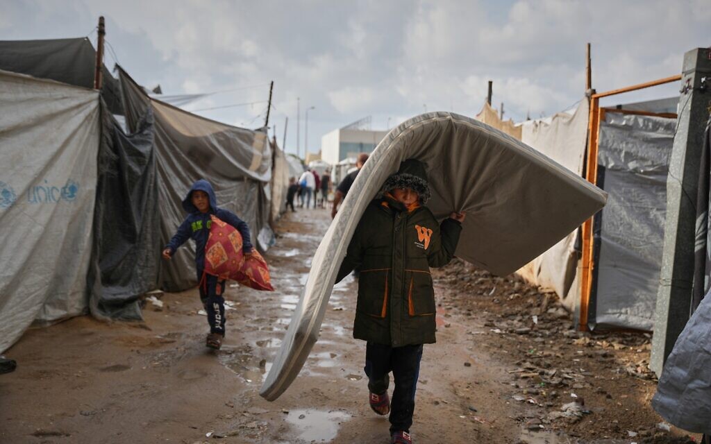 Salam Musa, 9, carries a mattress as he walks between tents after rainfall at a temporary camp in Deir al-Balah, in the central Gaza Strip, on Friday, November 14, 2025. (AP/Abdel Kareem Hana) Salam Musa, 9, carries a mattress as he walks between tents after rainfall at a temporary camp in Deir al-Balah, in the central Gaza Strip, on Friday, November 14, 2025. (AP/Abdel Kareem Hana)