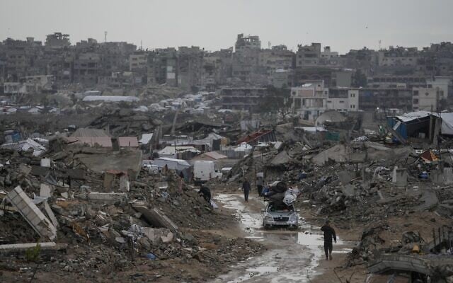 A car drives along a muddy road amid destroyed buildings in the Sheikh Radwan neighborhood of Gaza City, Friday, Nov. 14, 2025. (AP/Jehad Alshrafi)