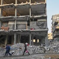 People walk by a gutted apartment building where residents used fabric to replace the walls at the Al-Shati camp in Gaza City, November 18, 2025. (AP Photo/Jehad Alshrafi)