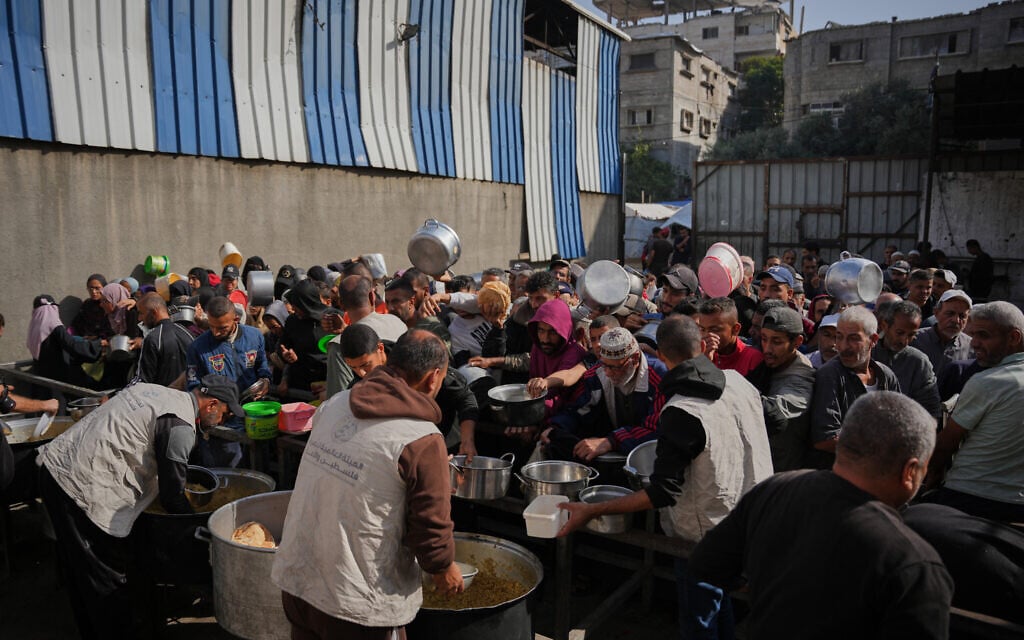 Palestinians gather to receive donated food at a community kitchen in Nuseirat, central Gaza Strip, Wednesday, Nov. 19, 2025. (AP Photo/Abdel Kareem Hana)