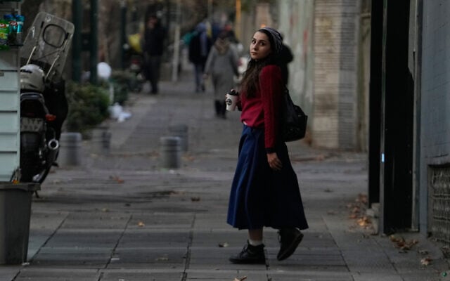 A woman holds her drink as she walks on a sidewalk in northern Tehran, Iran, November 20, 2025. (AP Photo/Vahid Salemi)