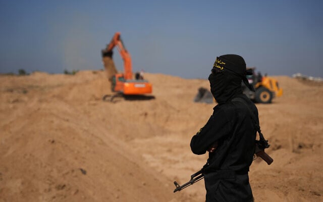 A Palestinian Islamic Jihad operative stands as PIJ and Egyptian workers ostensibly search for the bodies of hostages, north of Nuseirat, in the Gaza strip, on November 21, 2025. (AP Photo/Abdel Kareem Hana) A Palestinian Islamic Jihad operative stands as PIJ and Egyptian workers ostensibly search for the bodies of hostages, north of Nuseirat, in the Gaza strip, on November 21, 2025. (AP Photo/Abdel Kareem Hana)