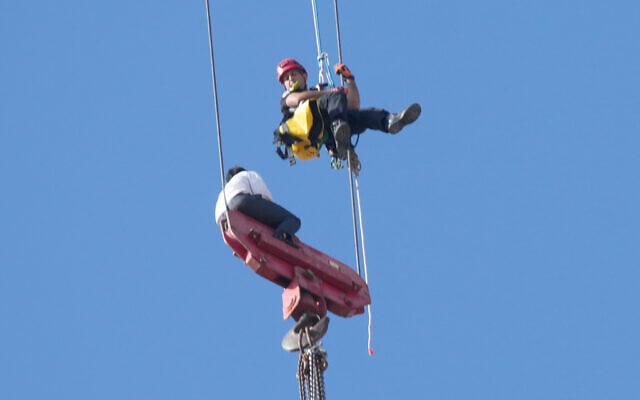 A teenager is rescued from a crane platform atop a skyscraper, where he dangled 36 stories up in the air for hours, in Jerusalem, Nov. 24, 2025. (AP Photo/Ohad Zwigenberg)