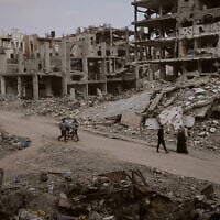 Palestinians walk among the ruins of destroyed buildings in Gaza City Monday, Nov. 24, 2025. (AP Photo/Jehad Alshrafi)