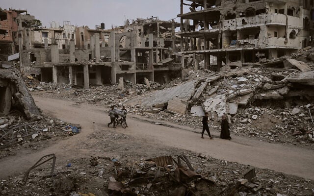 Palestinians walk among the ruins of destroyed buildings in Gaza City, Nov. 24, 2025. (AP Photo/Jehad Alshrafi)