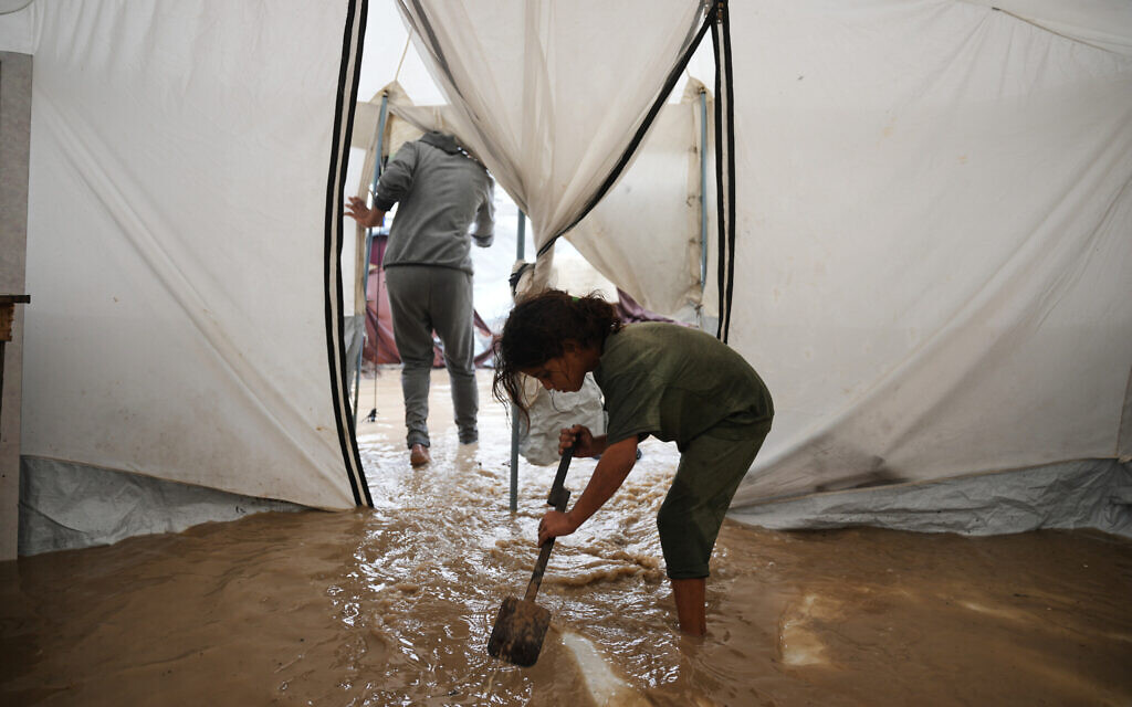 Saja Fayyad, 7, tries to clear water from her family's flooded tent at a temporary camp for displaced Palestinians after heavy rainfall in Deir al-Balah, central Gaza Strip, on November 25, 2025. (AP Photo/Abdel Kareem Hana)