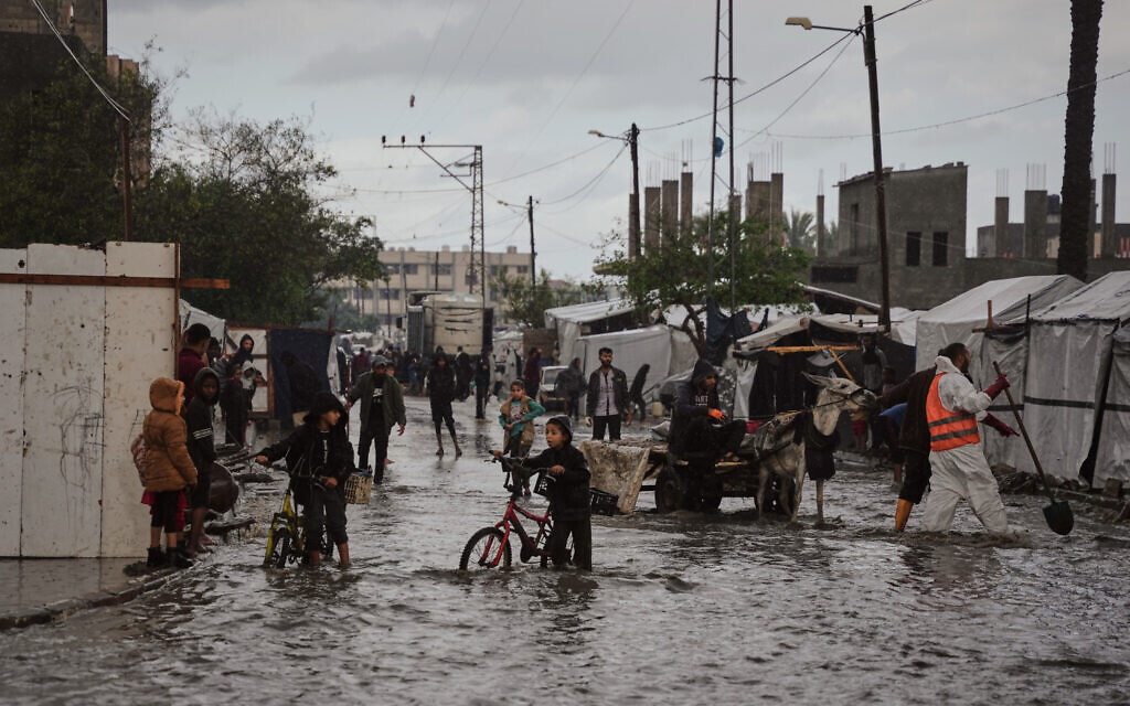 Palestinians walk through a flooded street next to a temporary tent camp after heavy rainfall in Deir al-Balah, central Gaza Strip, Tuesday, Nov. 25, 2025. (AP Photo/Abdel Kareem Hana) Palestinians walk through a flooded street next to a temporary tent camp after heavy rainfall in Deir al-Balah, central Gaza Strip, Tuesday, Nov. 25, 2025. (AP Photo/Abdel Kareem Hana)