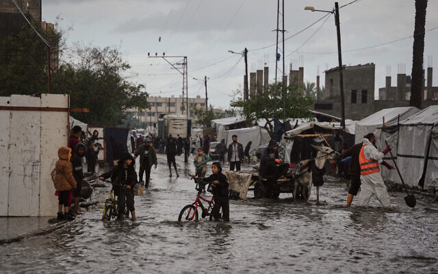 Palestinians walk through a flooded street next to a temporary tent camp after heavy rainfall in Deir al-Balah, central Gaza Strip, Tuesday, Nov. 25, 2025. (AP Photo/Abdel Kareem Hana) Palestinians walk through a flooded street next to a temporary tent camp after heavy rainfall in Deir al-Balah, central Gaza Strip, Tuesday, Nov. 25, 2025. (AP Photo/Abdel Kareem Hana)