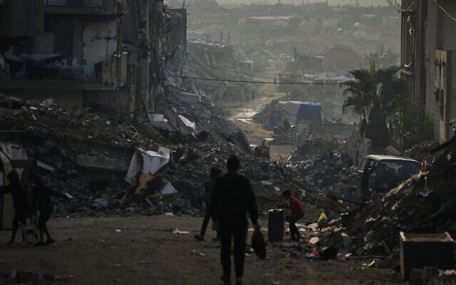 Palestinians walk through the destruction in Gaza City, November 29, 2025. (AP Photo/Abdel Kareem Hana)