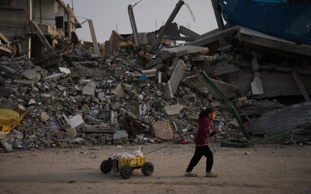 A girl carries bread as she walks past destruction left by Israeli air and ground operations in Gaza City, November 29, 2025. (AP Photo/Abdel Kareem Hana)