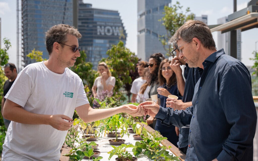Lavi Refael, founder and CEO of the Association For Urban Farming (L), speaks with a visitor at The Azrieli Garden in Tel Aviv (Courtesy/Association For Urban Farming)