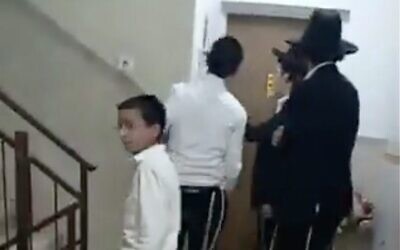 Haredi extremists chant "Traitor" and bang on the door of Shas MK Yinon Azoulay's apartment in Ashdod, November 19, 2025. (X screenshot)